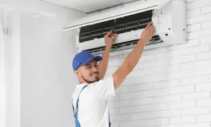 Tecnico con cappellino blu esegue la sanificazione aria condizionata, controllando i filtri per un'aria più pulita.