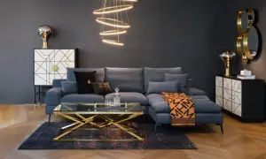 Nowoczesny, **soft loft salon** z szarą sofą, złotym stolikiem kawowym i designerską lampą.