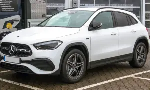 Biały Mercedes GLA, kompaktowy SUV, zaparkowany na mokrym parkingu. Jego wymiary idealnie pasują do miejskiej dżungli.