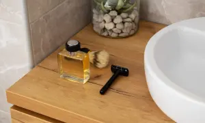 Elegancki, drewniany blat w łazience z buteleczką wody kolońskiej, pędzlem do golenia i maszynką.