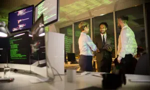 Zespół omawia strategię cyberbezpieczeństwa firmy przy monitorach z kodem.