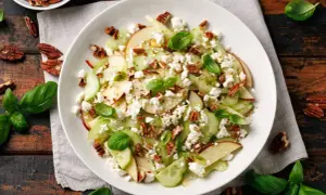 Sałatka z selera naciowego, jabłka, sera feta i orzechów pekan, udekorowana bazylią.