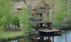 Drewniany domek na palach nad jeziorem, z pomostem i schodkami. Idealne łowiska z domkiem dla wędkarzy.