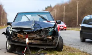 Un coche negro destrozado en la carretera, parece que fue un accidente grave. Un punto negro en la carretera que nadie quiere ver.