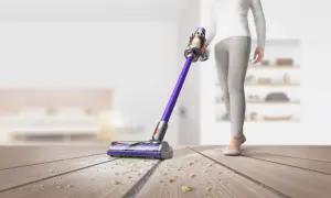 Osoba sprząta podłogę odkurzaczem Dyson.