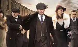 Gang w stylu Peaky Blinders, w tym Tommy Shelby z karabinem, idzie ulicą. Eleganckie płaszcze i kapelusze.