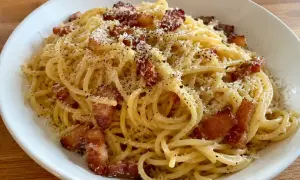 En krämig carbonara med pancetta, toppad med riven ost och svartpeppar. En klassisk italiensk rätt som ser utsökt ut.