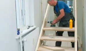 Man bygger trappa inomhus med skruvdragare och trälim.