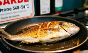 Poisson entier doré dans une poêle, prêt pour une recette gastronomique facile.