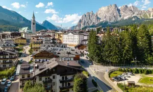 Vue d'un village pittoresque niché au pied des Dolomites en Italie, avec des maisons traditionnelles et une église imposante.
