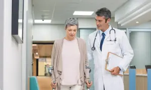 Lekarz wspiera pacjentkę po urazie, która porusza się o kulach. Postęp w leczeniu traumatologii jest widoczny.