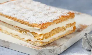 Una deliziosa torta diplomatica, stratificata con soffice crema e sfoglia croccante, spolverata di zucchero a velo.
