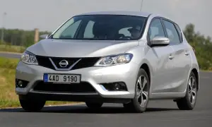 Srebrny Nissan Pulsar w ruchu drogowym. Kierowca w kapeluszu za kierownicą. Wiele pozytywnych nissan pulsar opinie.