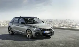 Szary Audi RS1 z brązowymi felgami stoi na dachu z widokiem na miasto.