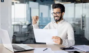 Uomo sorridente esulta con un foglio in mano, pensando a ex festività godute cosa sono.