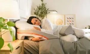 Woman sleeping peacefully on a specialized pillow designed to help with snoring. This pillow offers support for a comfortable sleep position, showing como poner la almohada para no roncar.
