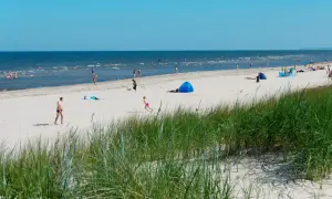 Menschen genießen einen sonnigen Tag am Strand der Ostsee. Nach der Fahrt mit dem Zug von Berlin ist dies eine willkommene Erfrischung.