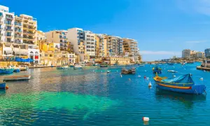Malta: kolorowe łodzie kołyszą się na turkusowej wodzie, a w tle piętrzą się białe budynki. Idealne miejsce, by poczuć śródziemnomorski klimat i wydać ostatnią malta waluta.