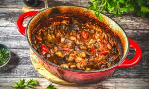 Herzhaftes Kalbsgulasch im roten Bräter, ein köstliches Rezept mit Paprika und Zwiebeln, bereit zum Servieren.