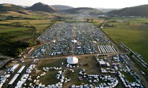 Vasto accampamento di tende e camper per il festival celtico Montelago, immerso in un paesaggio collinare verdeggiante.