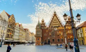 Der Marktplatz in Breslau mit dem historischen Rathaus und bunten Häusern. Ein sonniger Tag am Bahnhof Breslau.