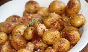 Un plat de pommes de terre grenaille au four, dorées et croustillantes, parsemées de sel et d'herbes.