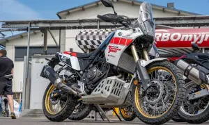 Biało-czerwony motocykl Yamaha Ténéré 700 z złotymi felgami, zaparkowany na zewnątrz.