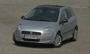 Srebrny Fiat Grande Punto z czarnym dachem i nowymi żarówkami, gotowy do jazdy po brukowanej nawierzchni.