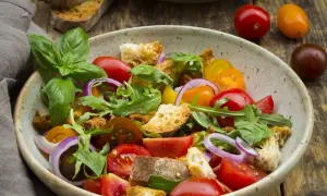 Bunter Salat mit Tomaten, Brotstücken und Rucola, verfeinert mit einem Hauch Balsamico Dressing.