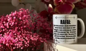 Kubek z imieniem Rafał i opisem jego znaczenia, otoczony bukietami różowych kwiatów. Idealny prezent na imieniny Rafała.