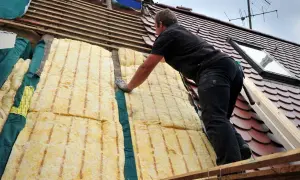 Dachdecker verlegt Dämmung. Energetische Sanierung Pflicht: So wird das Haus winterfest und spart Heizkosten.
