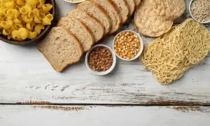 Kromki chleba, makaron, ryż, kukurydza, soczewica i płatki owsiane na białym tle.