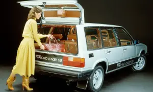 En kvinna i gul klänning lastar en väska i en silverfärgad Volvo concept car från 80-talet.