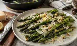 Délicieuse recette d'asperges vertes poêlées, garnies de copeaux de parmesan, de pignons de pin et de zeste de citron. Un plat simple et savoureux.
