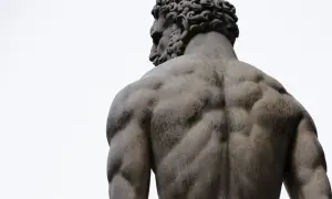 Dos des dieux Zeus, sculpture d'un homme musclé vu de dos, le ciel blanc en arrière-plan.