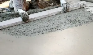 Pracownik wyrównuje świeży beton, przygotowując podłogę garażu. Dobry jaki beton na wylewkę do garażu to klucz do trwałej posadzki.