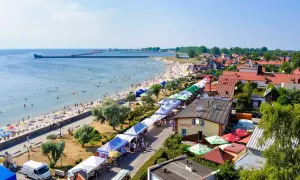 Hel: plaża pełna ludzi, stragany z pamiątkami i jedzeniem, idealne atrakcje dla dzieci.
