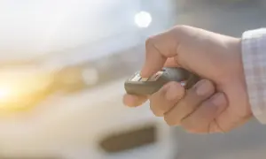 Dłoń naciska przycisk kluczyka samochodowego, aktywując immobilizer.