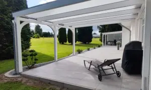 Modernes Terrassendach bauen: Ein Liegestuhl und Grill warten auf sonnige Tage unter dem neuen Dach. Der Garten lädt zum Entspannen ein.