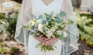 Panna młoda trzyma bukiet ślubny, w którym zastosowano technikę watowania we florystyce. Kwiaty są ułożone w luźny, naturalny sposób.