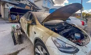 Spalony samochód elektryczny przed zniszczonym garażem. Może to być przyczyna, dlaczego w 2026 r. wzrosła liczba pożarów w warsztatach przez błędy w ładowaniu baterii.