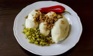 Trzy sycące kartacze z mięsem, posypane skwarkami, z dodatkiem ogórków kiszonych i papryczki chili.