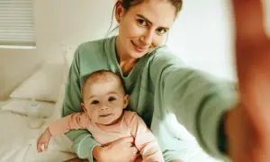 Uśmiechnięta mama z dzieckiem na rękach, czuje, kiedy macierzyństwo zaczyna cieszyć.