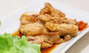 Straccetti di pollo succulenti e dorati, serviti su un piatto bianco con insalata fresca e carote sottaceto.