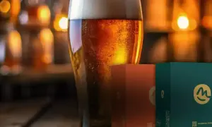 Bicchiere di birra dorata con bollicine, accanto a scatole di birra celiaci.