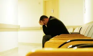 Man sitter med huvudet i händerna i en väntsal, kanske redo att sluta med fluoxetin.