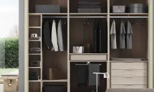 Un armario moderno y funcional, ideal para quienes buscan cómo diseñar un armario con estilo. Ropa colgada, cajones y estantes organizados.