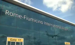 Szklana fasada lotniska Rome-Fiumicino International Airport, z odbijającym się samolotem i znakiem Gate 17.