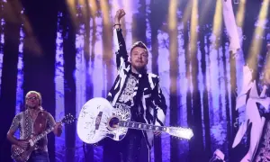 Piotr Kupicha z zespołem na scenie, w tle fioletowy las.
