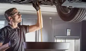 Mécanicien effectuant une vidange d'huile. Il est important de savoir vidange tous les combien pour l'entretien de votre véhicule.